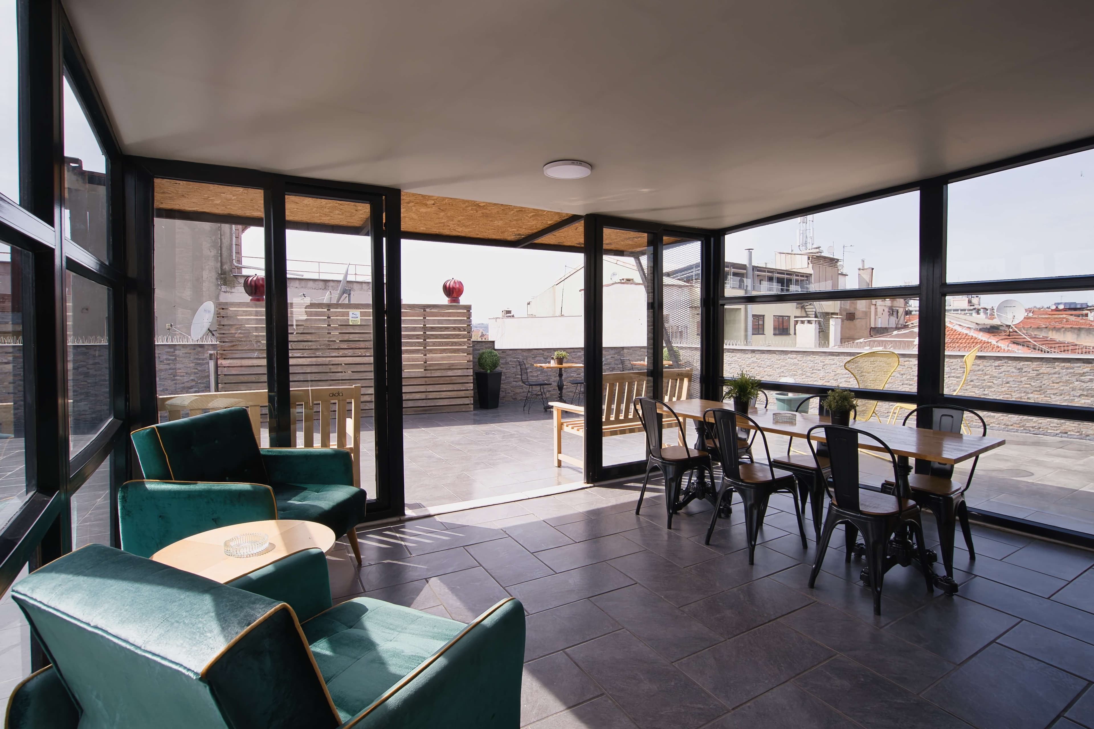 Rooftop sunroom with green velvet armchairs and city views