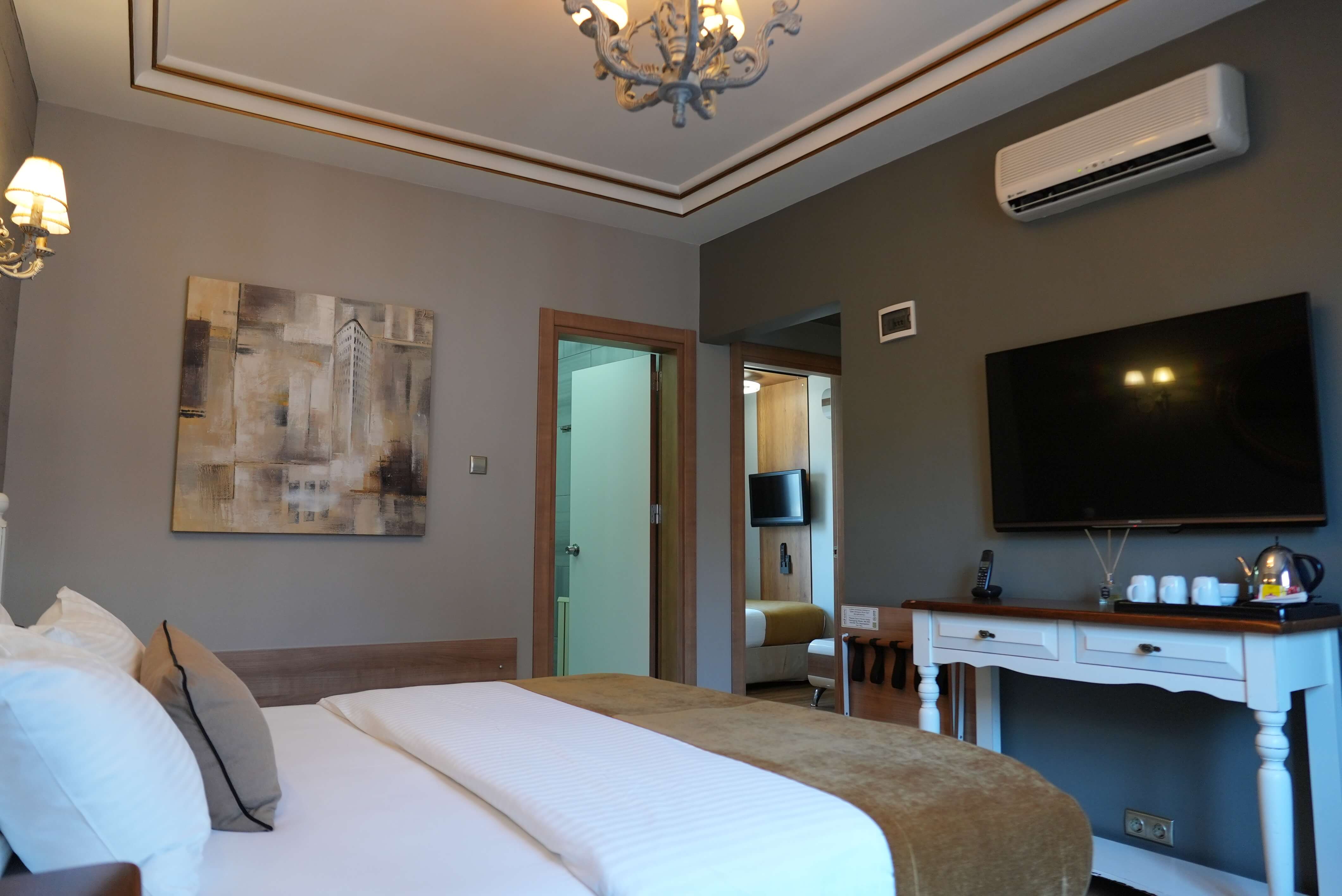 Suite main bedroom from the corner, with a wall-mounted TV and the doorway through to the second bedroom