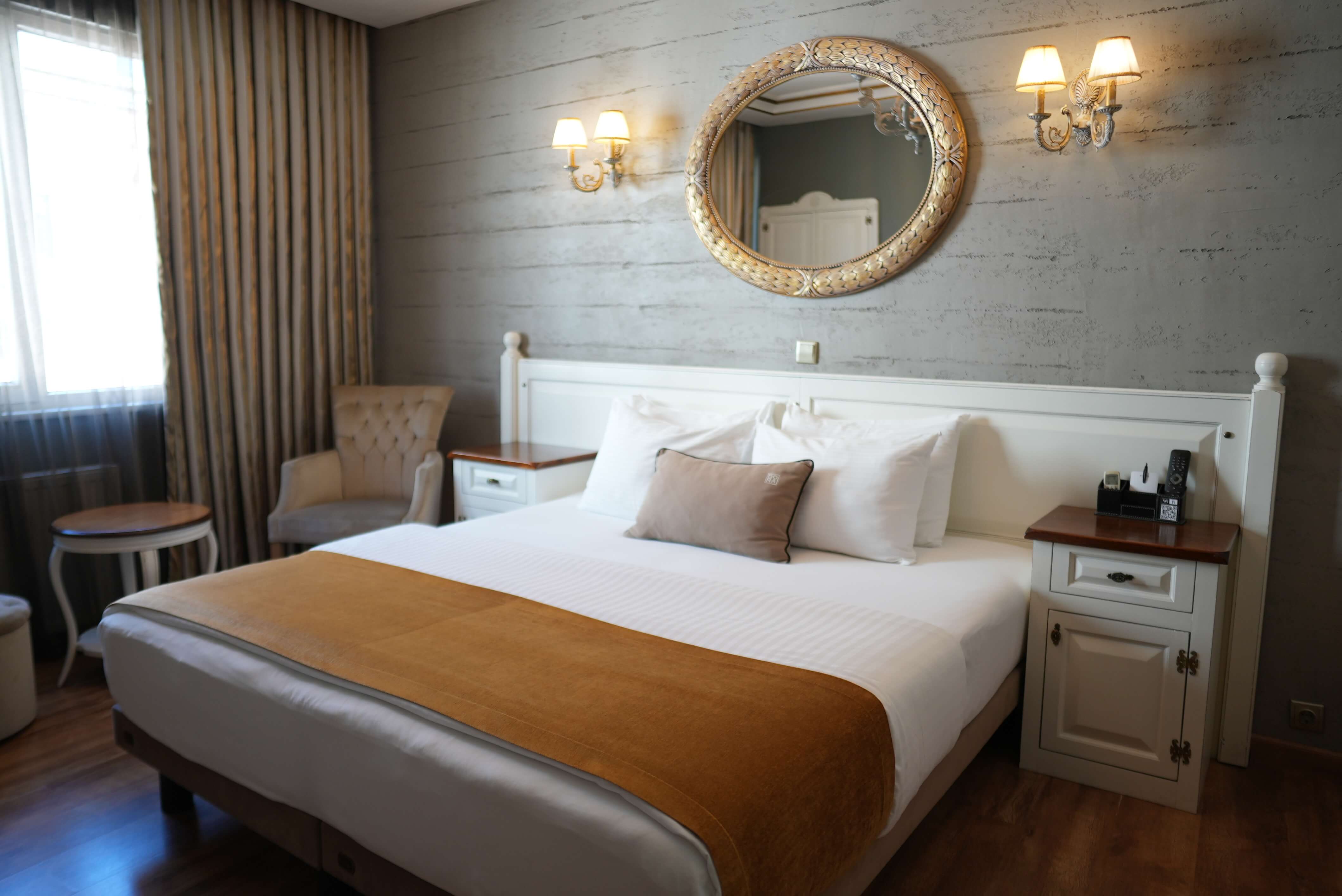 Suite main bedroom with a king bed, a gilded oval mirror and paired wall sconces