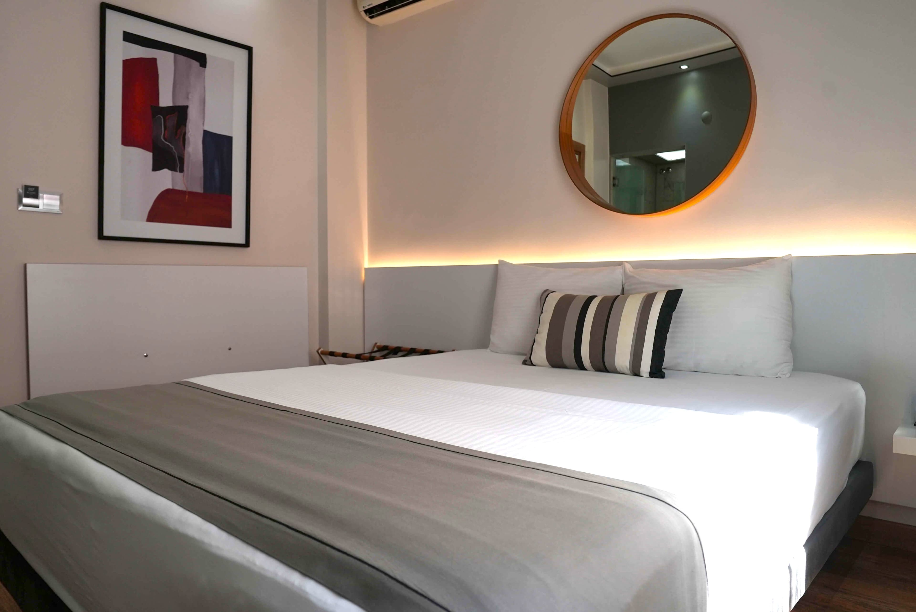Standard double: the bed from the side, with framed artwork and a backlit headboard