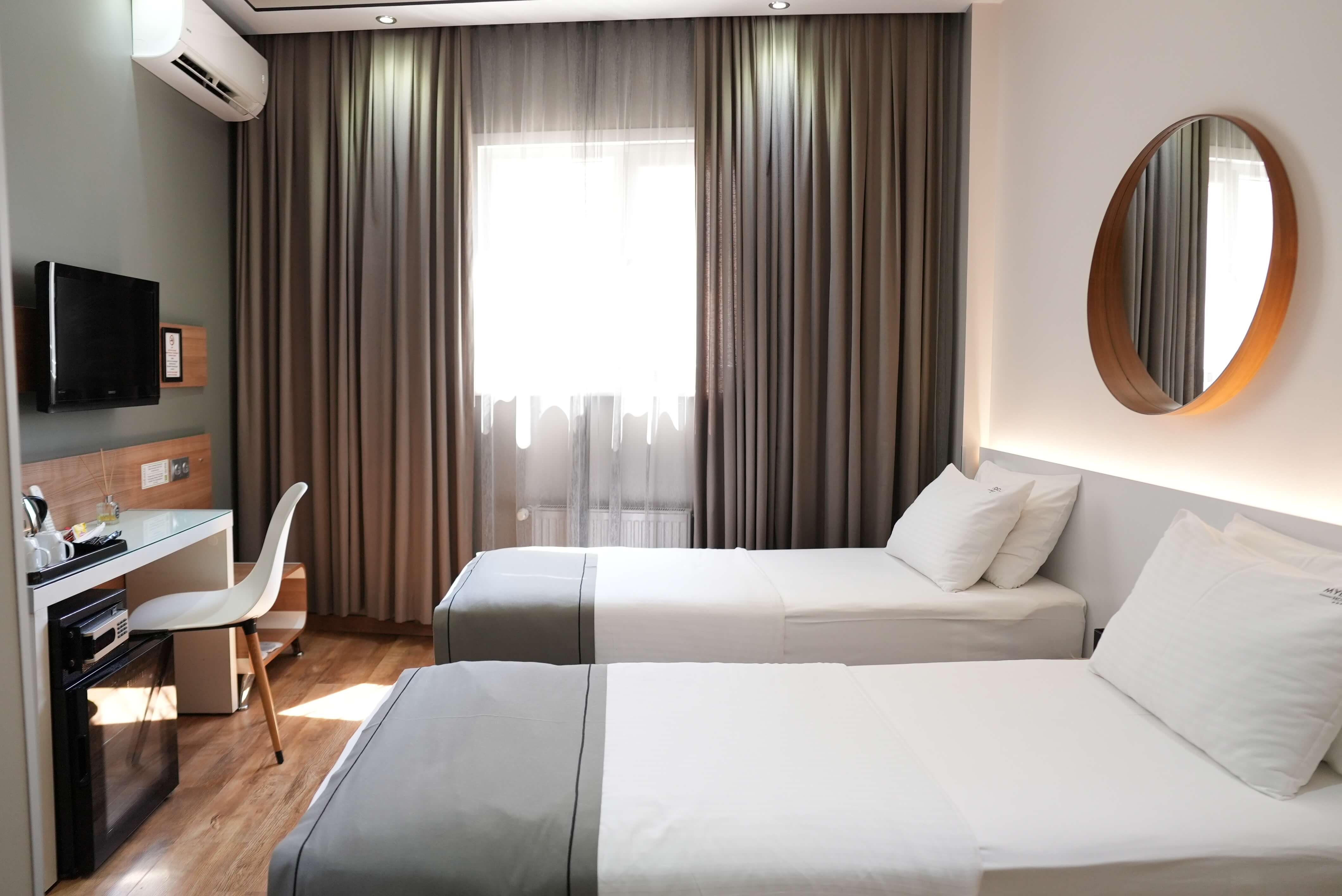 Standard twin: the room from the corner, with wall-mounted TV, desk and minibar